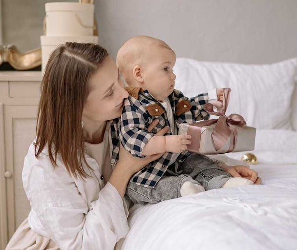 madre tiene bambino neonato con regalo in mano